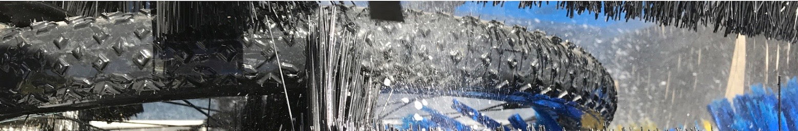 Close-up of a knobbly bicycle tyre being washed between the cycleWASH brushes