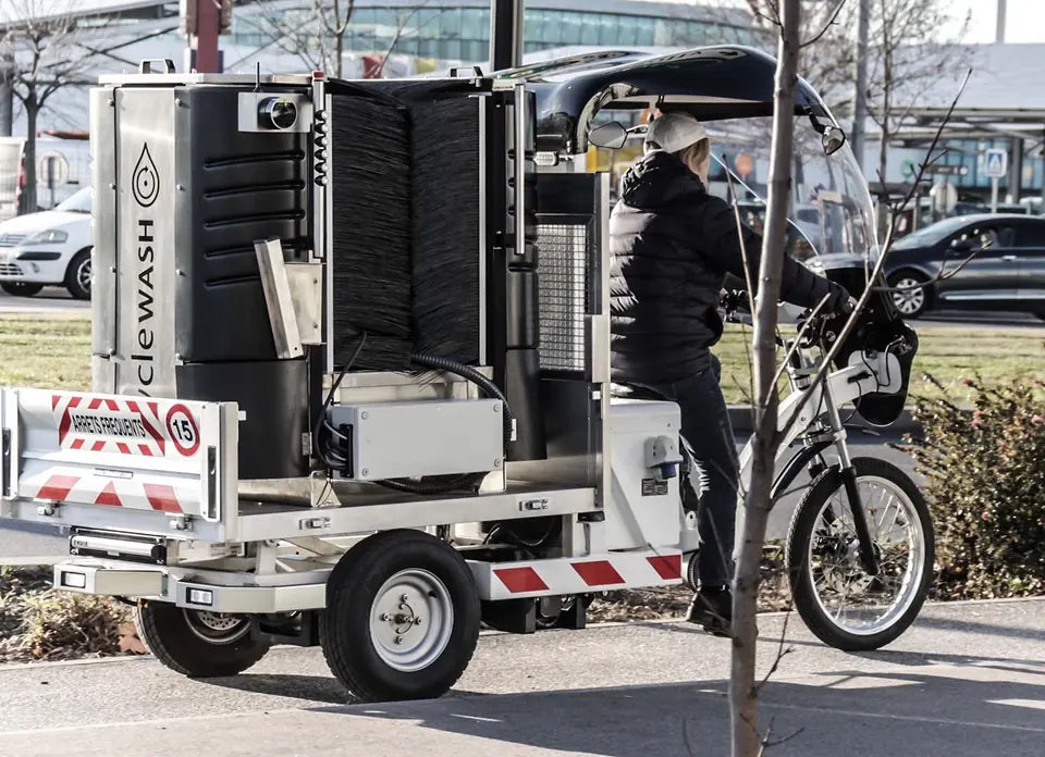 The cycleWASH Go on its trailer, hitched behind an e-bike on a city street