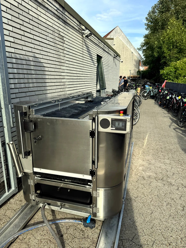 Pro on the paved yard at a bike dealer, alongside the customer racks