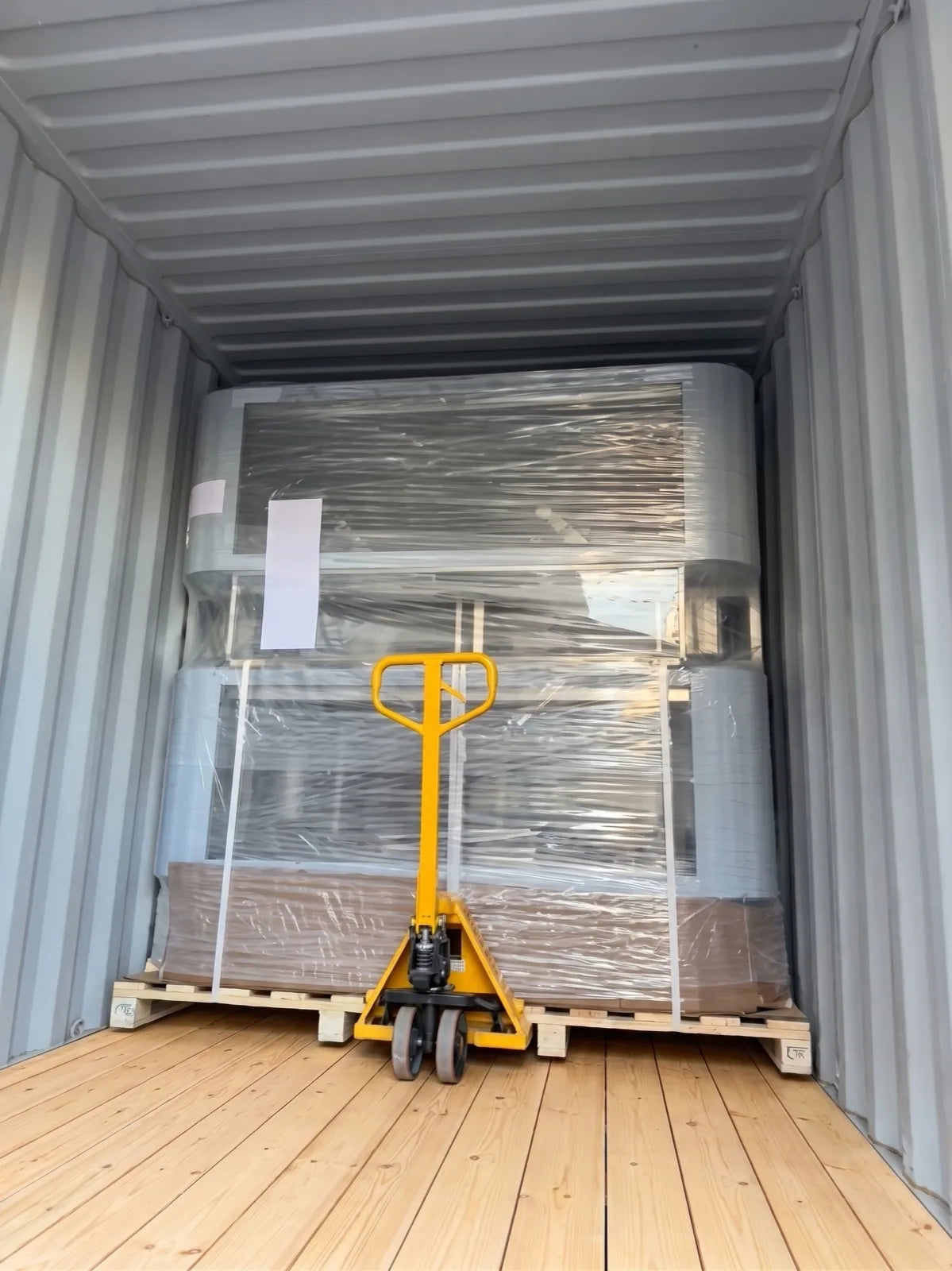 Two cycleWASH machines stacked and wrapped inside a shipping container, pallet truck in front