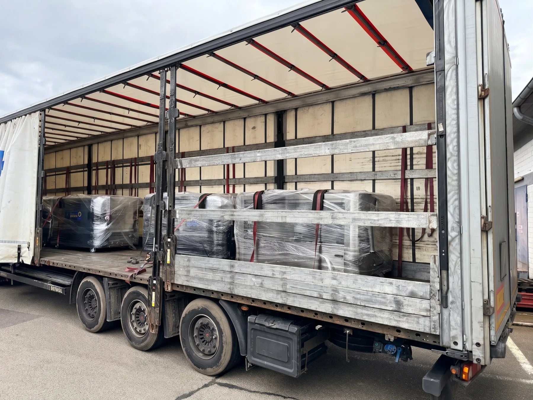 Four pallet-wrapped cycleWASH machines strapped along the bed of a curtain-side trailer